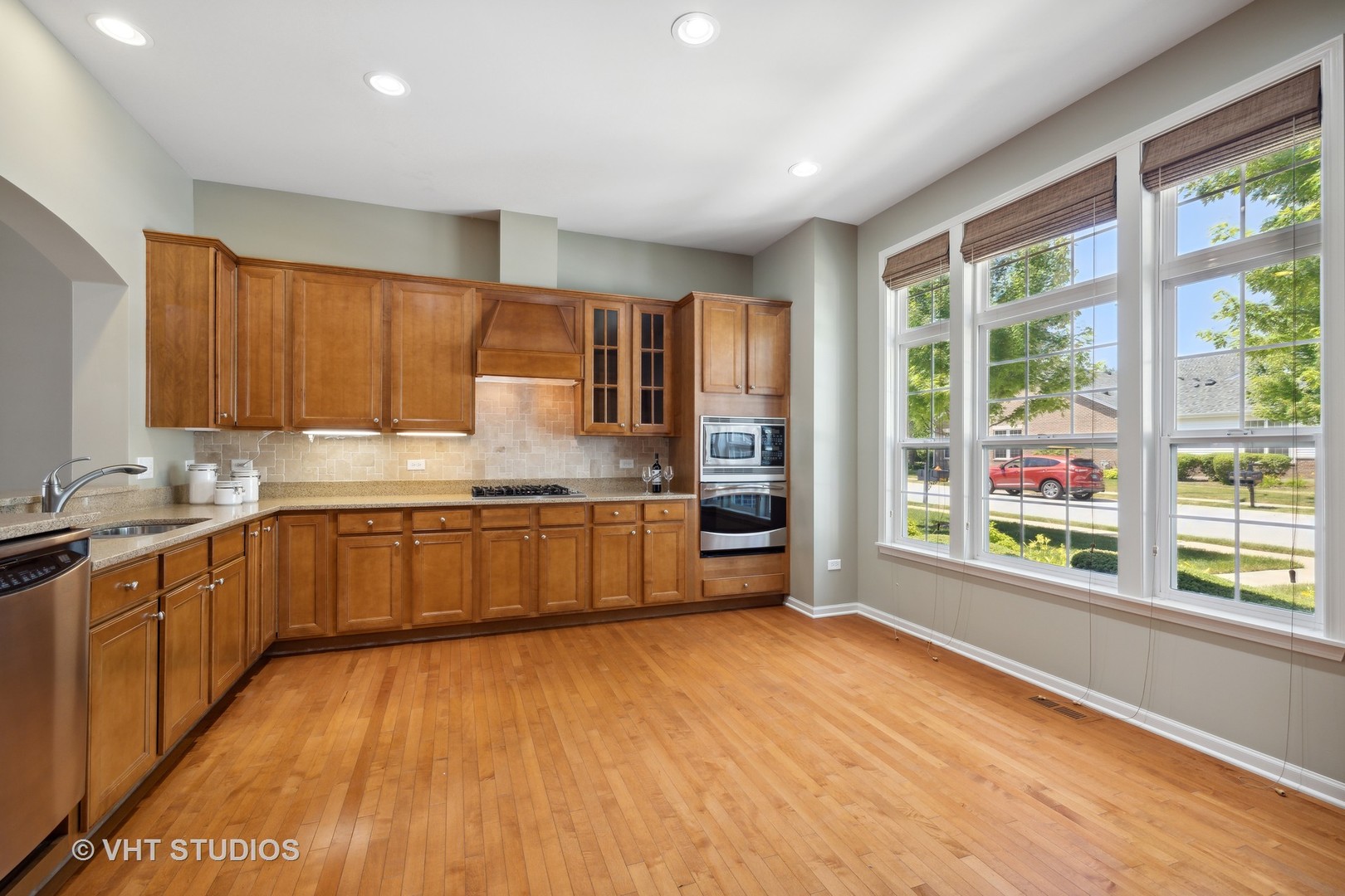2944 Normandy Circle Naperville, IL 60564 - Photo 5 of 38 a kitchen with stainless steel appliances granite countertop a stove a sink wooden cabinets and a large window