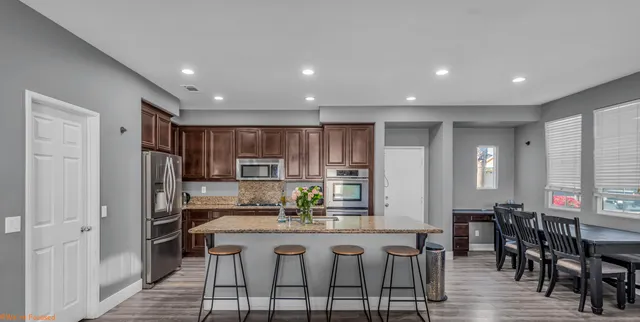 a kitchen with stainless steel appliances granite countertop a dining table chairs and granite counter tops