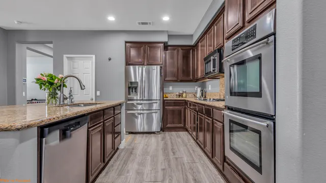 a kitchen with stainless steel appliances granite countertop a refrigerator a stove and a sink