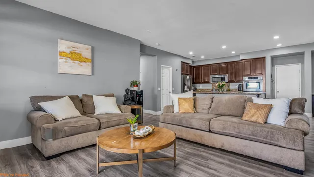 a living room with furniture kitchen view and wood floor