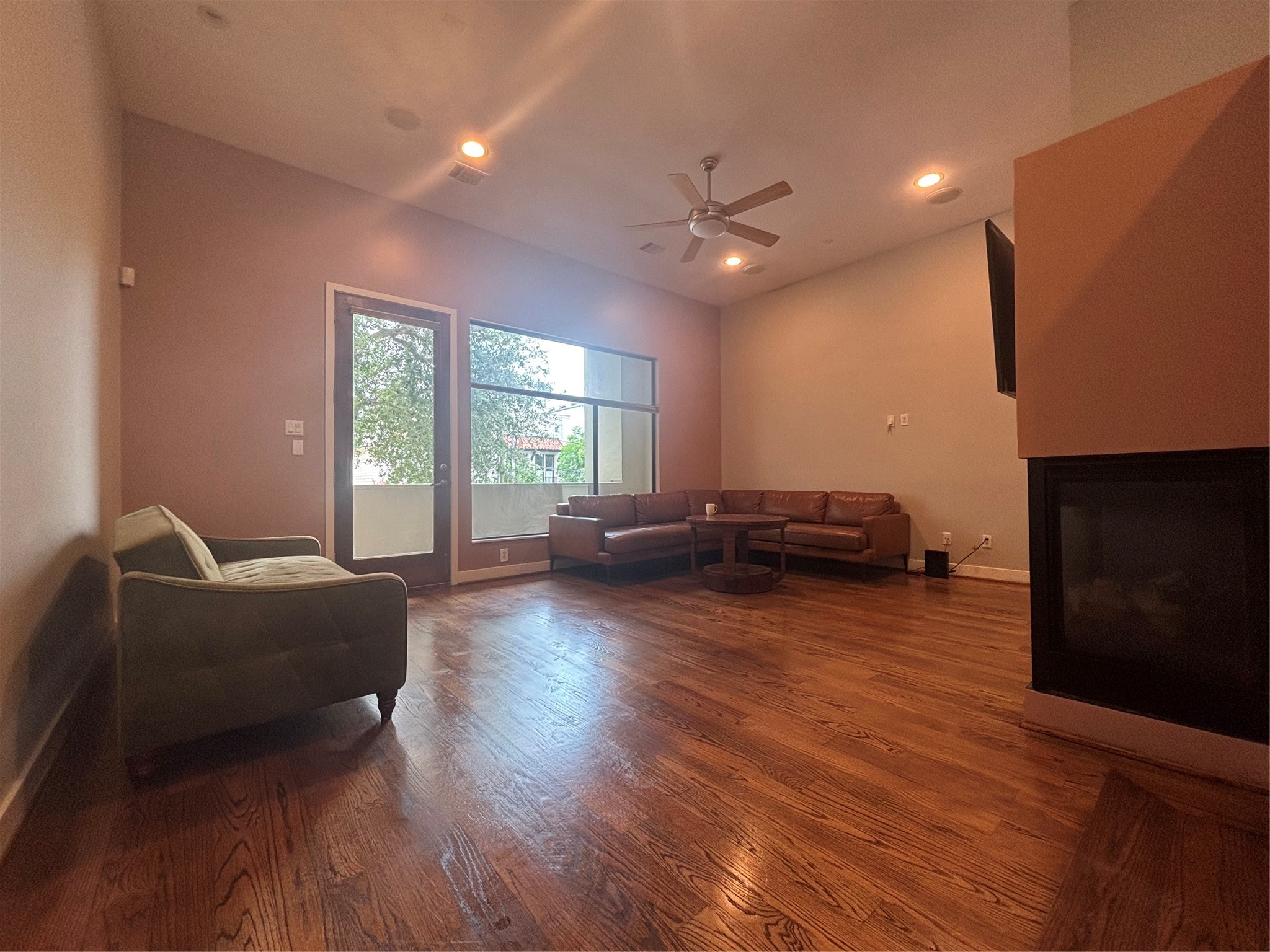 6016 Truro Street Houston, TX 77007 - Photo 1 of 26 Spacious open-concept living area featuring soaring ceilings, hardwood floors a contemporary fireplace, and abundant natural light with balcony access.