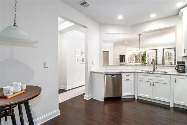 a large white kitchen with a sink a stove a dining table and chairs