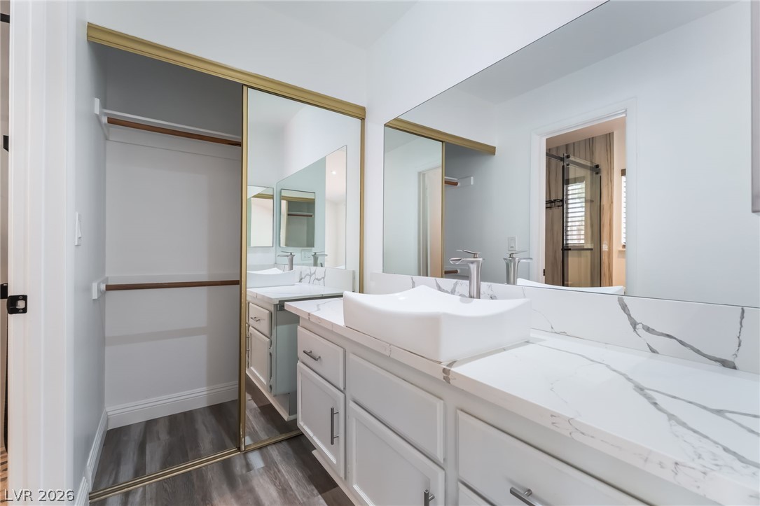 9028 Cypress Point Road Las Vegas, NV 89117 - Photo 19 of 39 Refined bathroom vanity with a vessel sink and marble-patterned countertops, accompanied by a mirrored closet with hanging space.