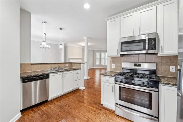 a kitchen with stainless steel appliances white cabinets and stove top oven