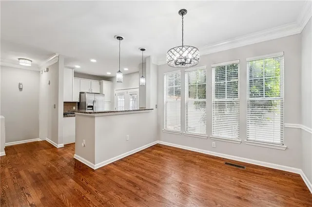 a view of an empty room with wooden floor and a kitchen