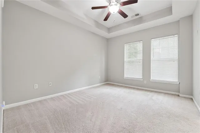 an empty room with chandelier fan and windows