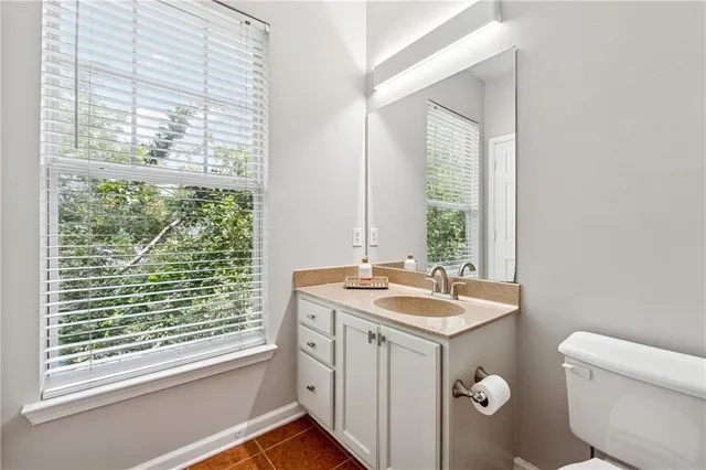 a bathroom with a granite countertop sink toilet and large window