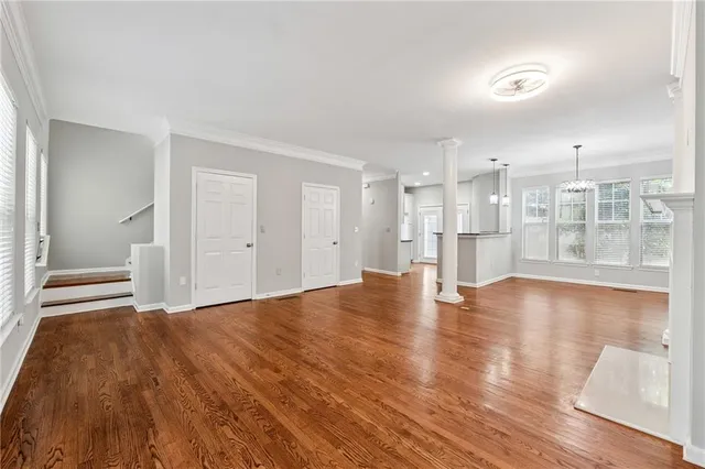 a view of empty room with wooden floor and kitchen view