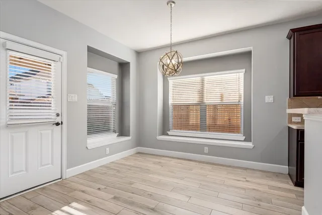 a view of an empty room with a window and wooden floor