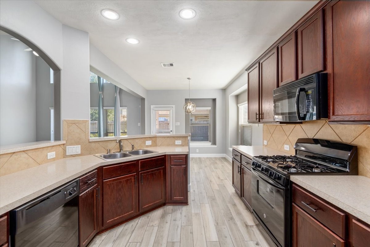 8203 Rudy Brook Way Spring, TX 77379 - Photo 15 of 37 a kitchen with stainless steel appliances granite countertop a sink stove and cabinets