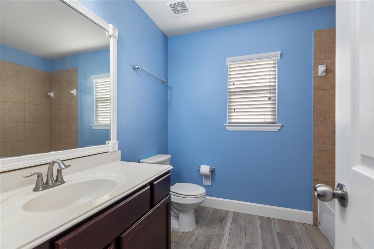 8203 Rudy Brook Way Spring, TX 77379 - Photo 31 of 37 a bathroom with a granite countertop toilet a sink a mirror and a window