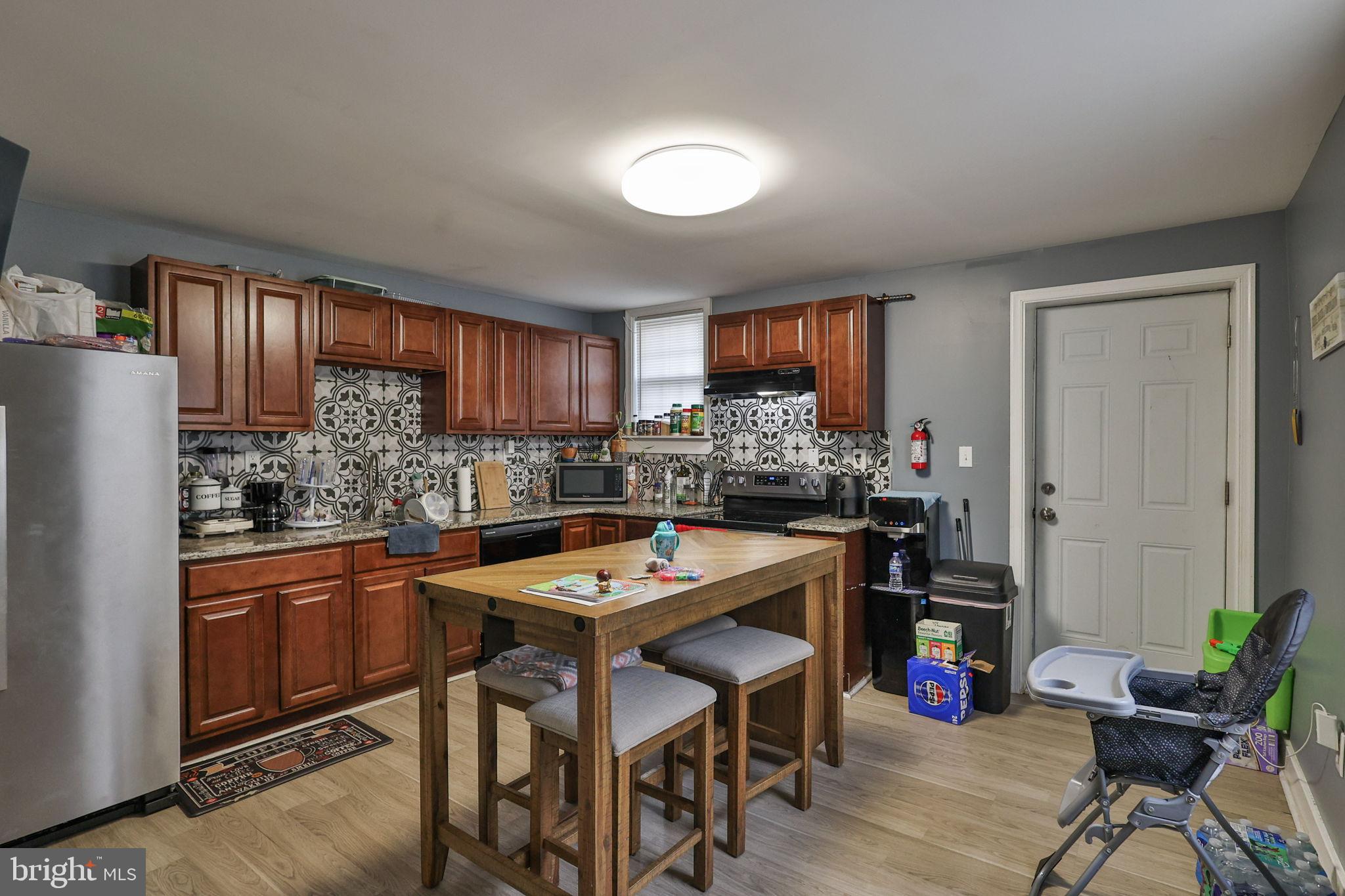 714 Ward Street Chester, PA 19013 - Photo 14 of 40 a kitchen with granite countertop a refrigerator a stove a sink a dining table and chairs with wooden floor