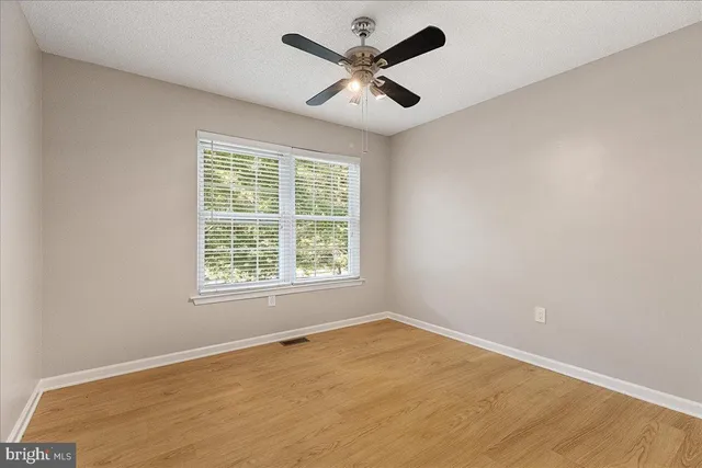 an empty room with a window and a ceiling fan