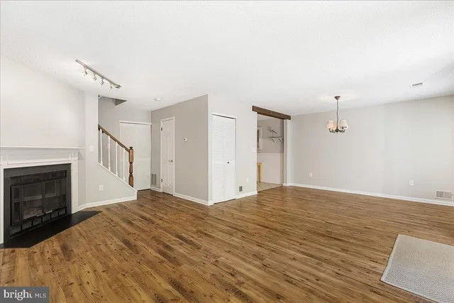 a view of an empty room with wooden floor and a fireplace