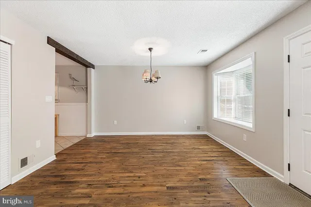 an empty room with wooden floor cabinet and windows