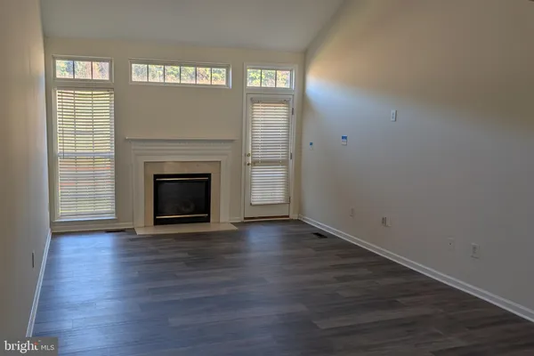an empty room with wooden floor fireplace and windows