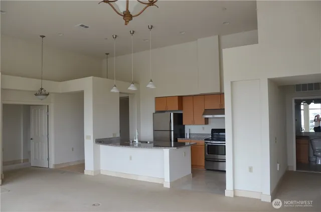 a view of a kitchen with kitchen island a counter top space stainless steel appliances and cabinets