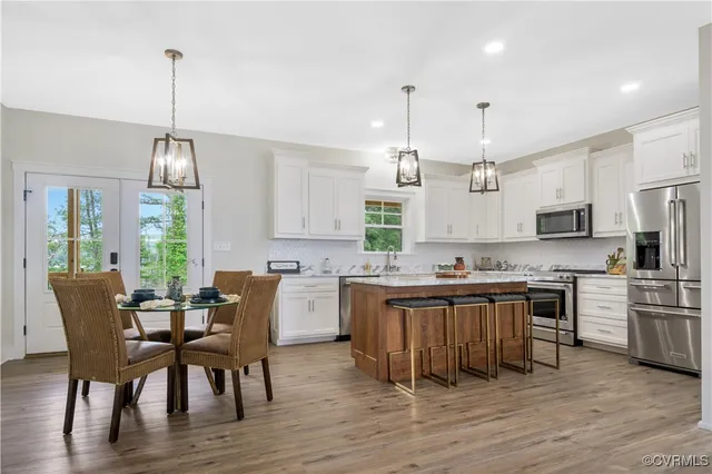 a kitchen with kitchen island granite countertop a stove top oven a sink dishwasher a dining table and chairs with wooden floor