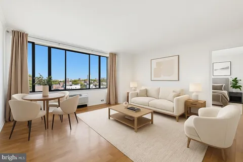 a living room with furniture a rug a lamp and a large window