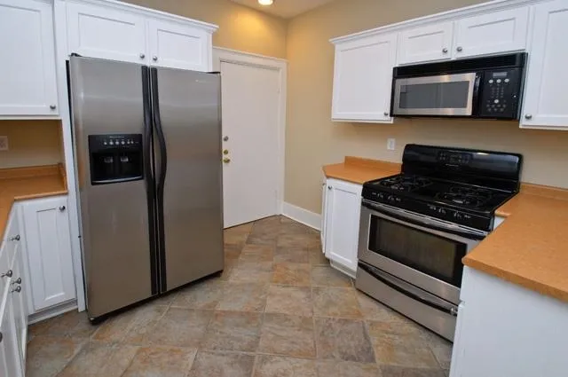 a kitchen with granite countertop a refrigerator stove and microwave