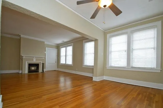 a view of an empty room with wooden floor fireplace and a window