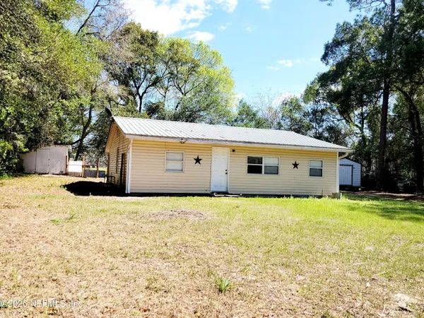 a front view of house with yard and trees in the background