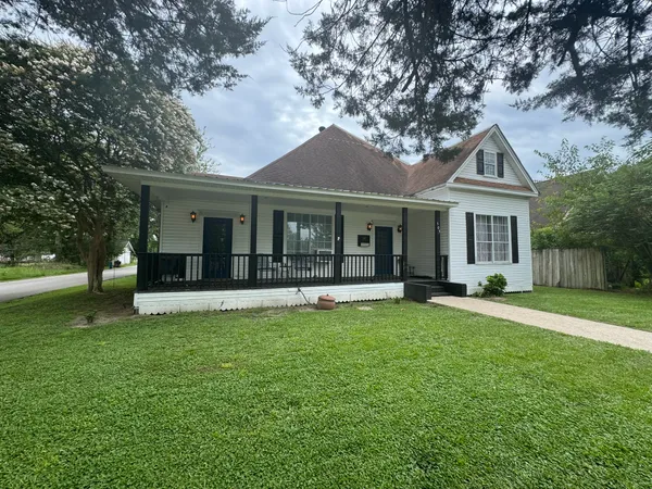 a front view of a house with a garden and trees