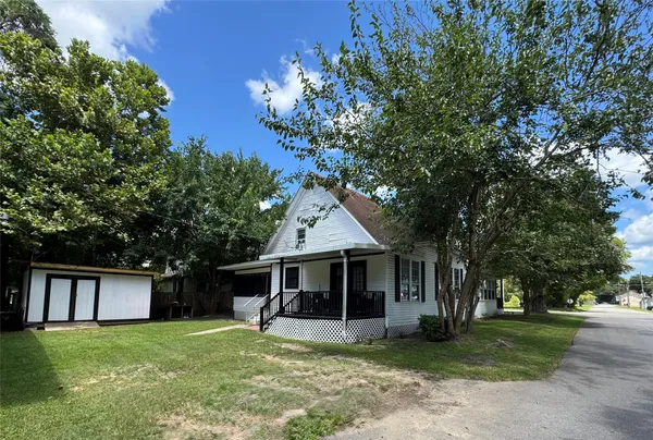 a front view of a house with a garden and trees
