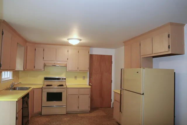 a view of a kitchen with fridge and wooden floor