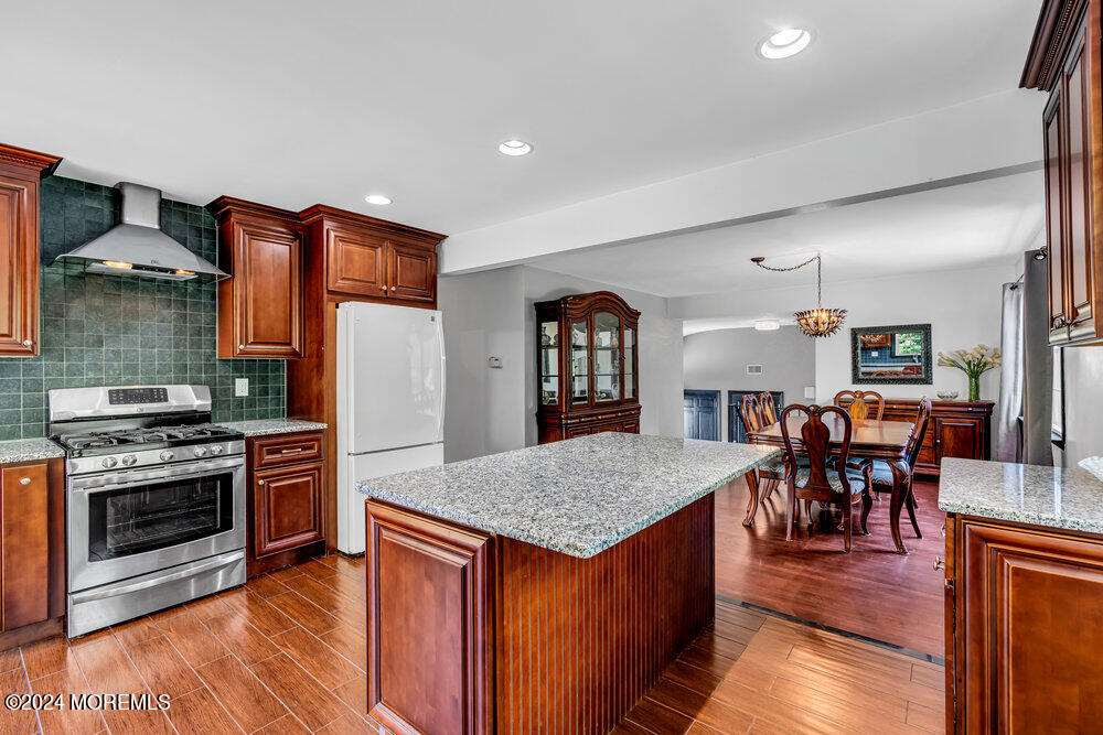 9 Comanche Drive Middletown, NJ 07716 - Photo 21 of 69 a kitchen with stainless steel appliances granite countertop a stove top oven a sink a dining table and chairs