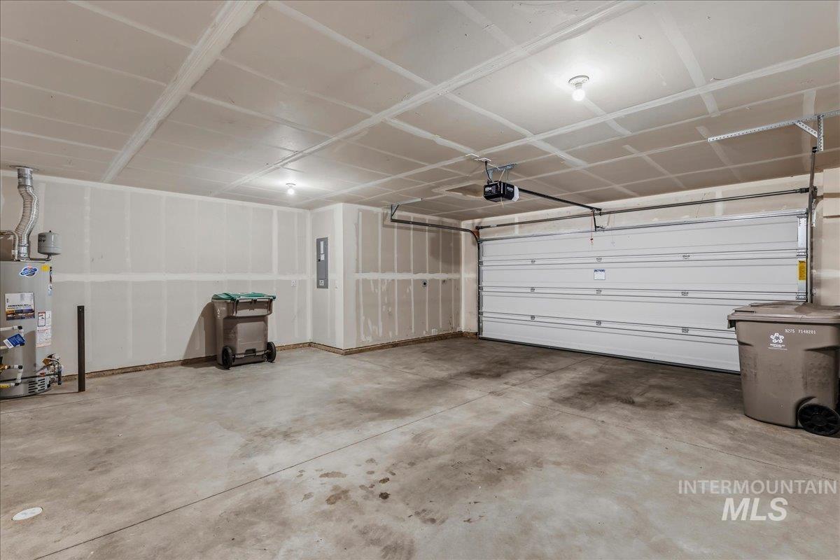 12475 West Victory Road Boise, ID 83709 - Photo 25 of 26 Spacious garage with an overhead door, automatic opener, concrete flooring, exposed ceiling joists, and a water heater
