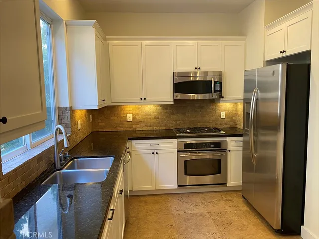 a kitchen with granite countertop a stove and a refrigerator