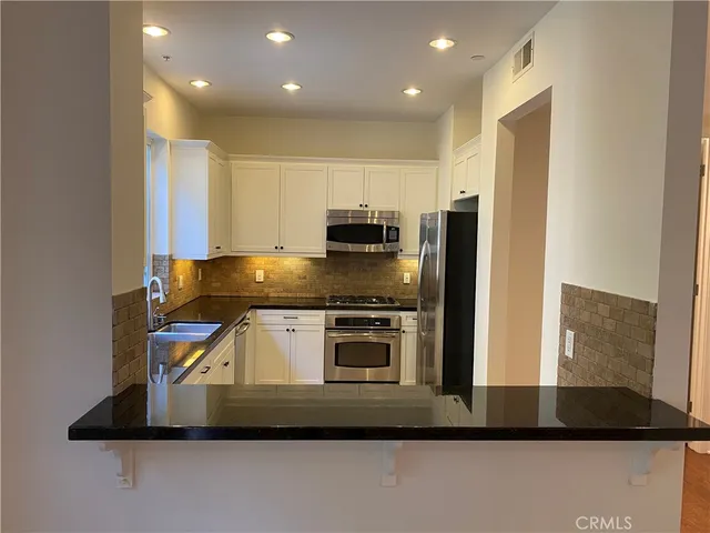 a kitchen with kitchen island a sink stainless steel appliances and cabinets