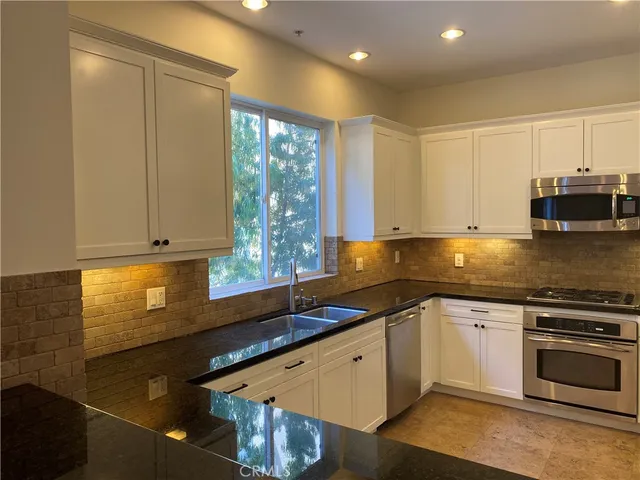 a kitchen with stainless steel appliances granite countertop a sink a stove and a microwave