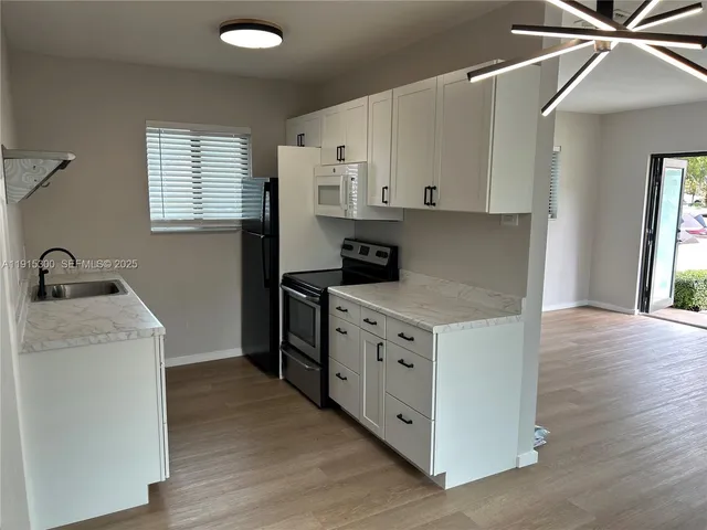 a kitchen with cabinets appliances and a wooden floor