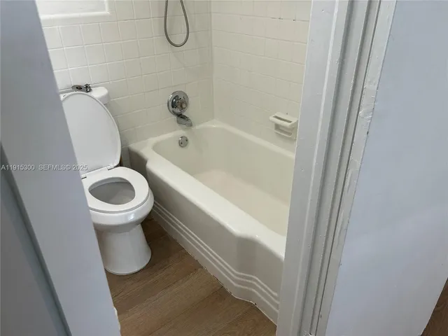 a bathroom with a granite countertop toilet and a tub
