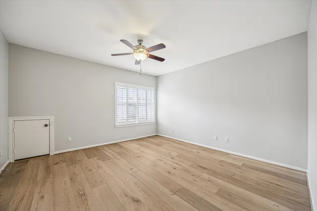 an empty room with wooden floor fan and windows
