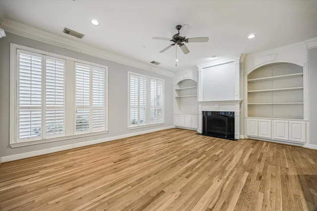 a view of an empty room with a window and wooden floor