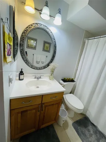 a bathroom with a granite countertop toilet sink and mirror