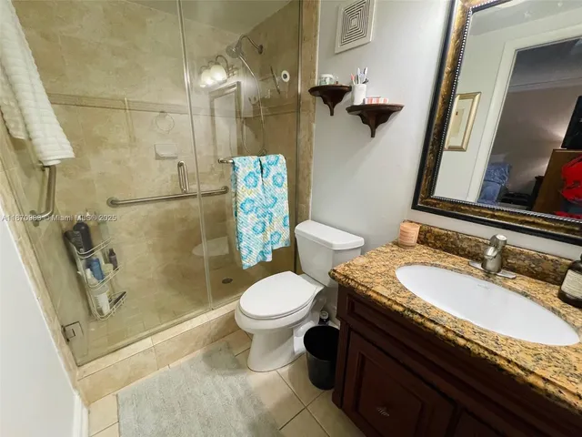 a bathroom with a granite countertop toilet sink and mirror