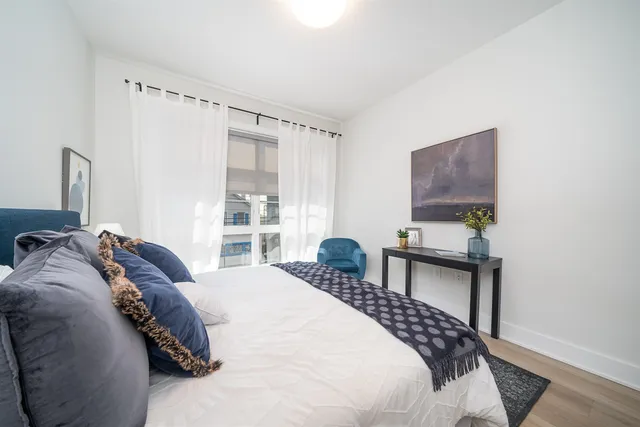 a bedroom with a bed table chair and a window