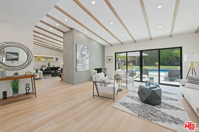 a living room with furniture a rug a flat screen tv and a large window