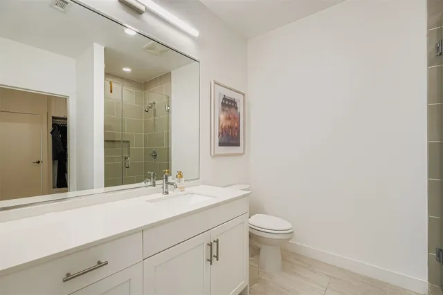 a bathroom with a granite countertop sink a toilet and a mirror