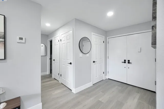 a living room with stainless steel appliances furniture wooden floor and a kitchen view