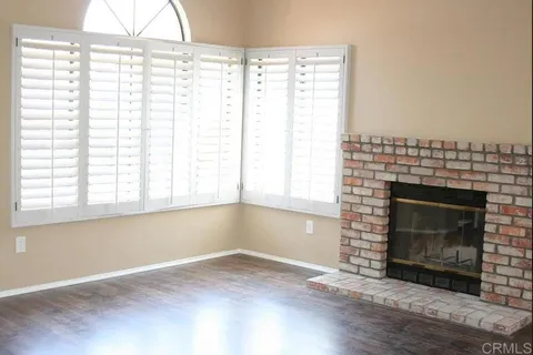 a view of empty room with wooden floor and a fireplace