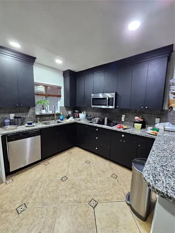 a kitchen with kitchen island granite countertop wooden cabinets a counter top space and stainless steel appliances