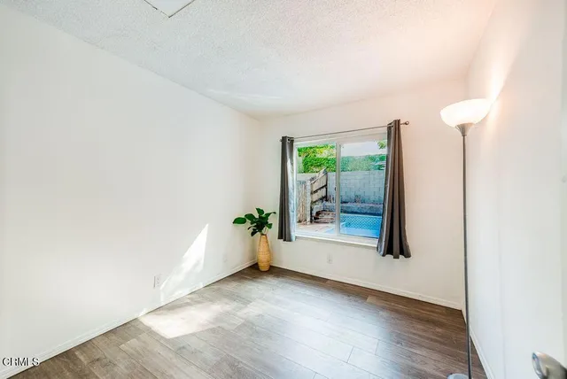 an empty room with floor to ceiling window and wooden floor