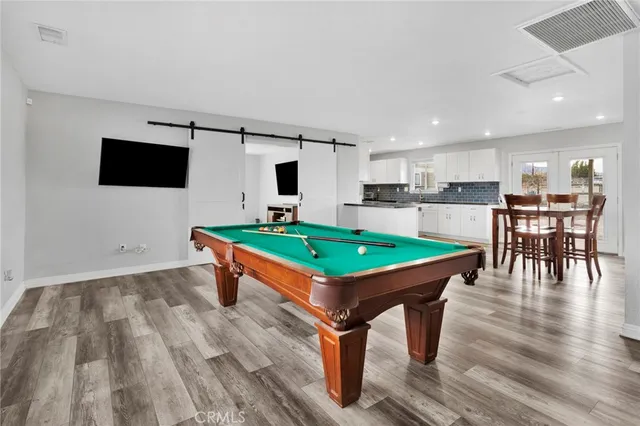 an room with pool table windows and kitchen view