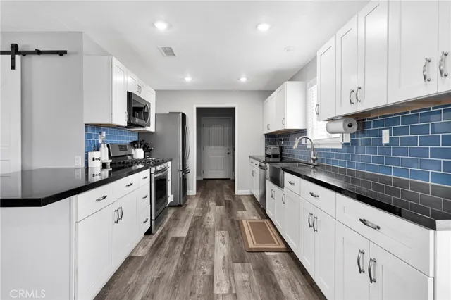 a large kitchen with stainless steel appliances granite countertop a stove a sink and white cabinets