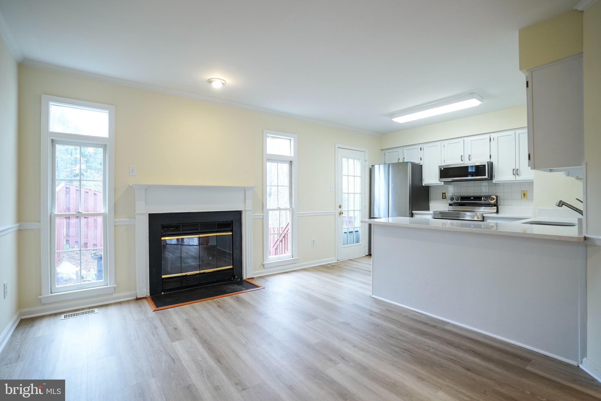 6903 Compton Lane Centreville, VA 20121 - Photo 8 of 35 a living room with stainless steel appliances a fireplace a flat screen tv and wooden floor